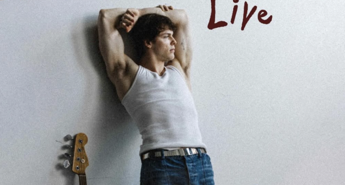 A man wearing a white tank top and jeans posing next to a guitar. Text to the right reads: LIVE